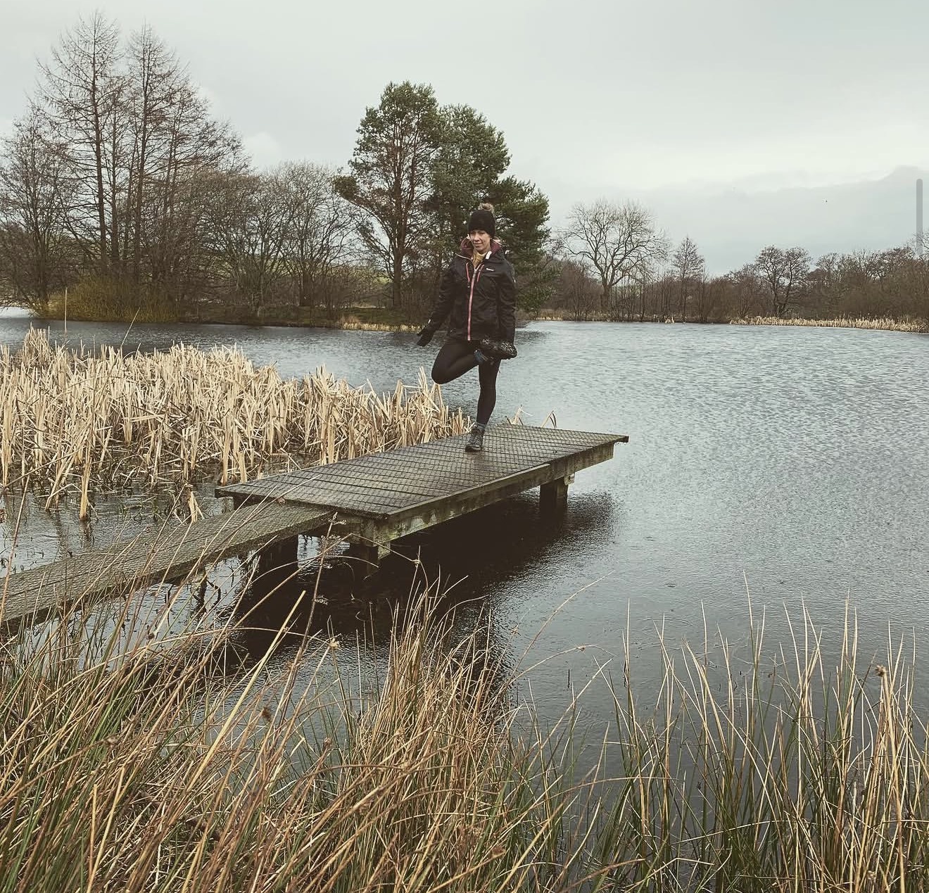 Tree pose on a wooden jetty over still winter water