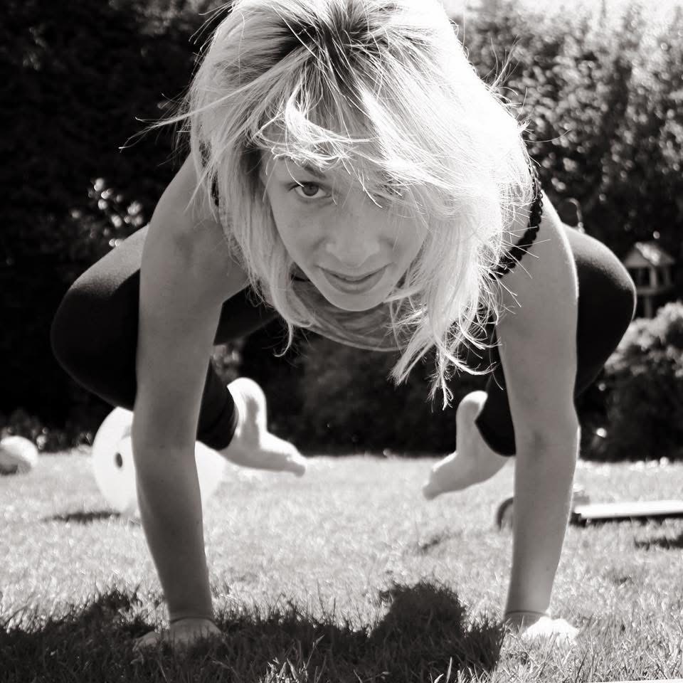 Crane pose balanced on the hands on sunlit grass, black and white